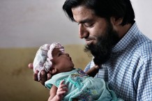 Shabir Kamal, 37 years old, property and land dealer, Fatima's husband, posing for the Every Newborn Action Plan with his newborn girl, 15 days old, at his mother in law's house. After delivering, according to tradition, Pakistani women stay at their mothers' houses for 40 days. Taxila, Punjab. Pakistan 2014