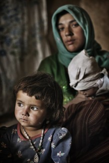 Kobra, 3 years old, and in the background her aunt Nazima, who does not know her age. Herat Province, Afghanistan, 2012.