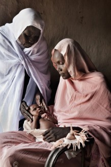 Midwife Rabha Abdalraheem Ahmed, 56 years old, visiting Raheeba Mohammed, 25 years old, and her forth newborn girl Madeena, 25 days old. Marin village, Rahad locality, Gedaref State. Sudan, 2015.