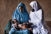 Maryam Mohammed, 24 years old, with her sixth newborn boy Abdalhaleem, 23 days old, and midwife Rabha Abdalraheem Ahmed, 56 years old, at Marin, Rahad. Gedaref State, Sudan, 2015.