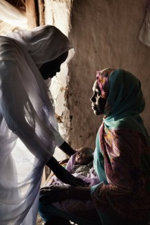 Midwife Rabha Abdalraheem Ahmed, 56 years old, visiting Sandlya Ibrahim, 25 years old, and her fifth newborn girl Marwa, 14 days old. Marin village, Rahad locality, Gedaref State. Sudan 2015.