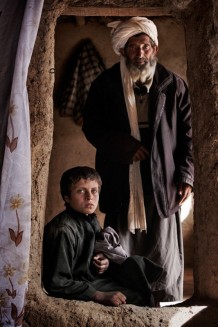 The camps of returning refugees or internally displaced populations become very quickly breeding grounds of sorrow. Diseases take hold faster in these impoverished, small temporary quarters, rife with violence, unemployment and children forced to labour and early marriage. The boy and the old man are both sick with TB.<br>Maslakh, IDP (internally displaced persons) camp. Province of Herat, 2012