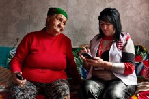 Zoya (left), 77, a beneficiary, and Oksana, 49, a local community worker, during a home visit. Zoya lives alone. She bakes bread and feeds the soldiers with what's left. She also makes them rugs from rags. In return, they occasionally lend her a hand, such as bringing her medicine. Oksana had a son who was a civilian prisoner of the Russians; the stress made her ill, but fortunately she managed to find him and have him released. Novopavlivka, Kharkiv Region. Ukraine, 2026